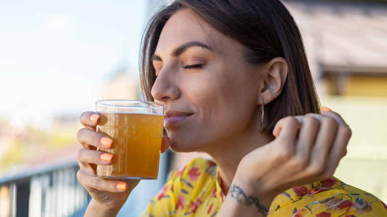 Woman sniffing kombucha in glass