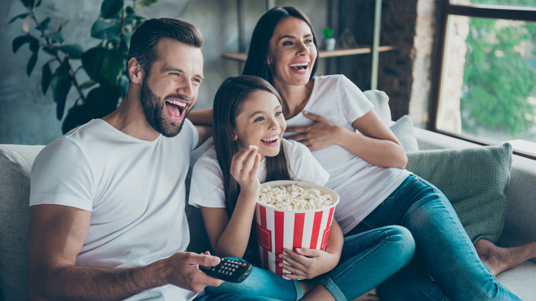 A family watches a movie while eating popcorn