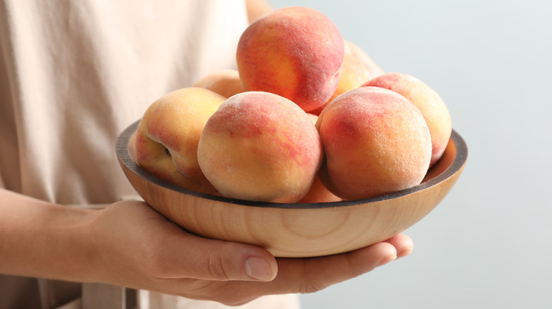 woman holding a bowl of peaches