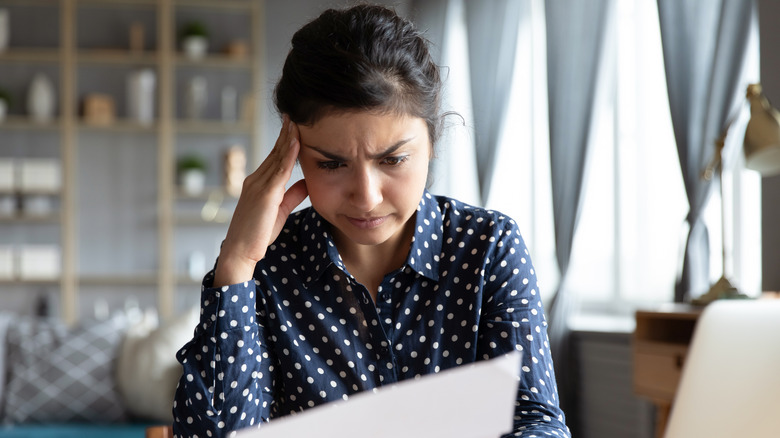 woman holding paper looking stressed