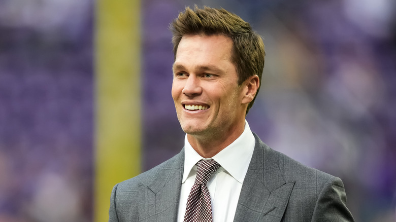 Tom Brady wearing a suit at a football game in 2024