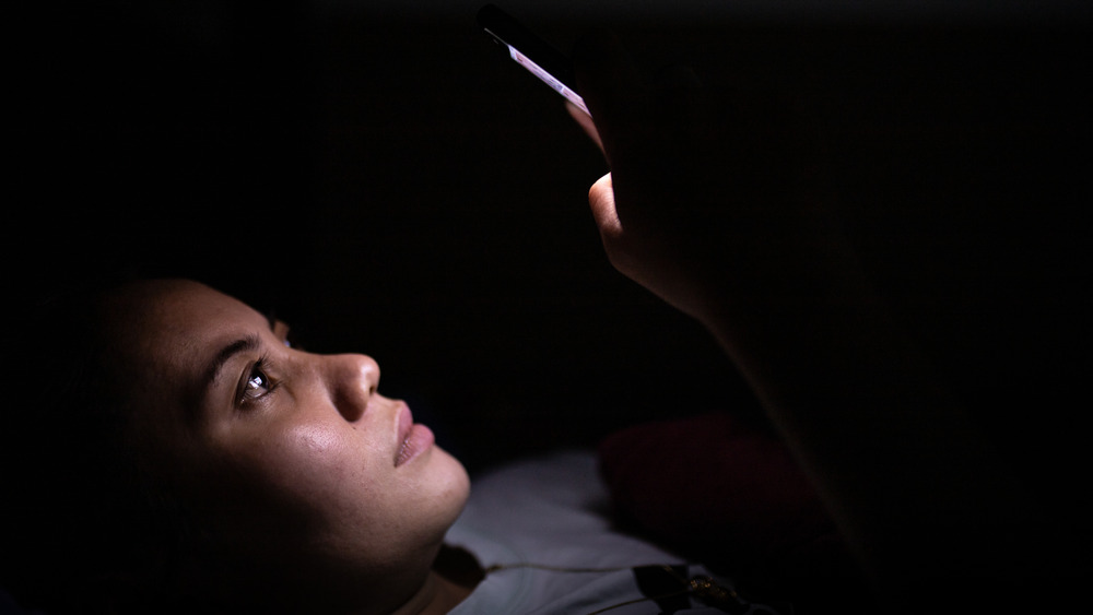 Woman looks at phone in the dark