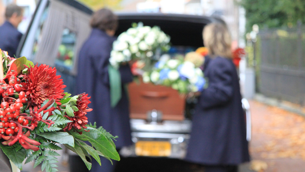 Mourners load a coffin into a hearse