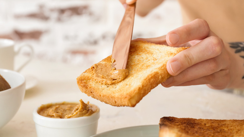 close up of spreading peanut butter on toast