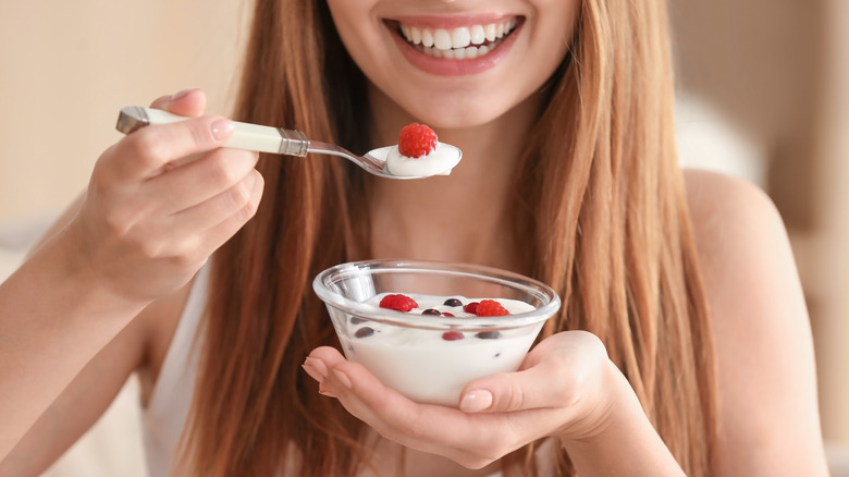 close up of smiling woman holding bowl of yogurt