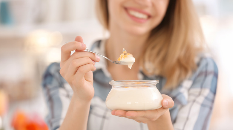 smiling woman holding spoon with yogurt