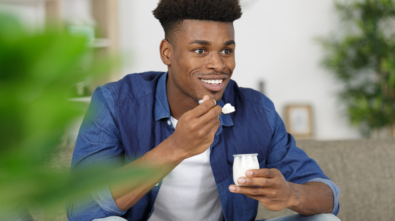 Man smiling and holding jar of yogurt