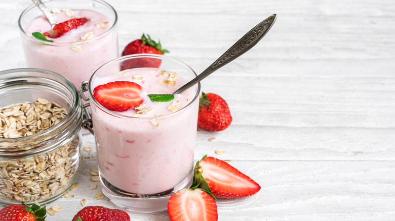two clear glasses filled with pink yogurt with strawberries