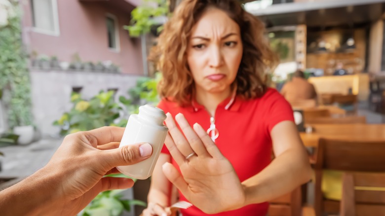 woman puts hand up to say no to extra salt