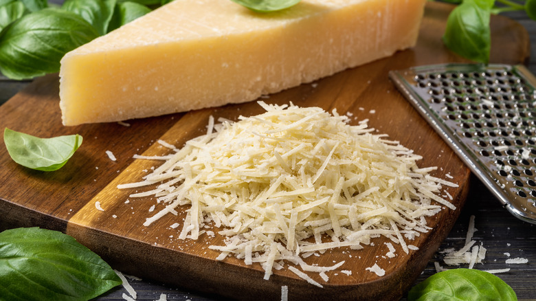 Shredded parmesan next to parmesan wedge