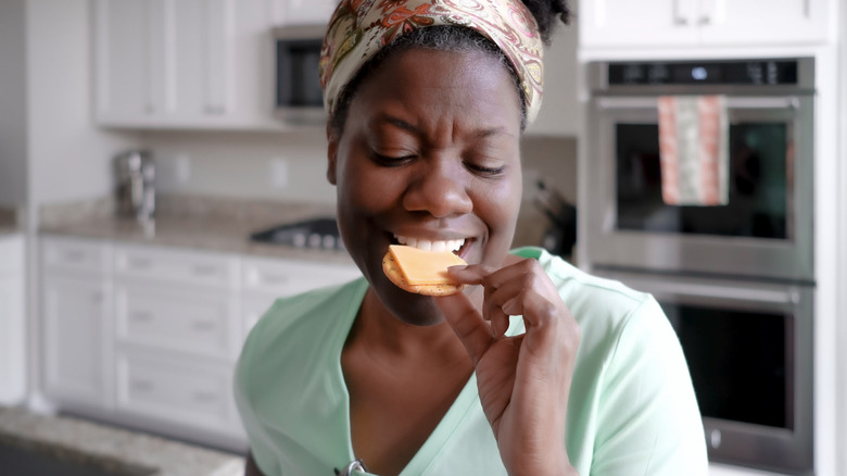 woman eating cheese on a cracker