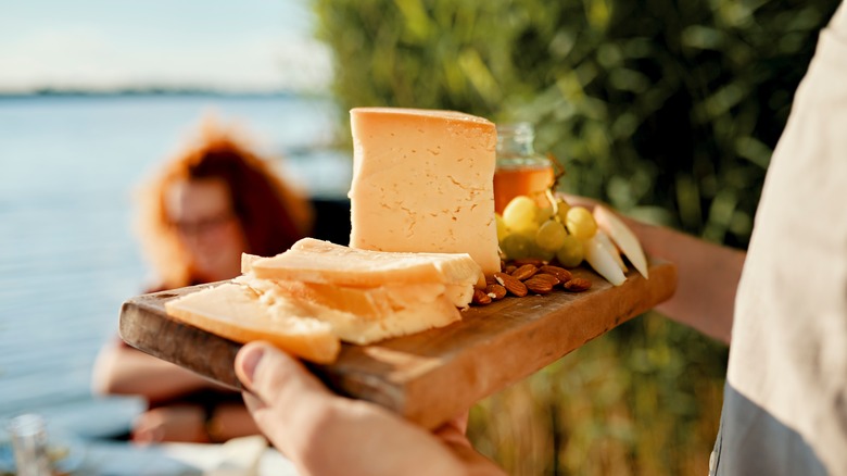 man's hands serving a cheese and nut platter