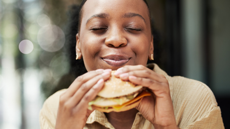 A woman enjoying a fast food hamburger