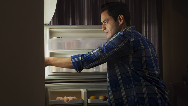Man reaching into fridge at night