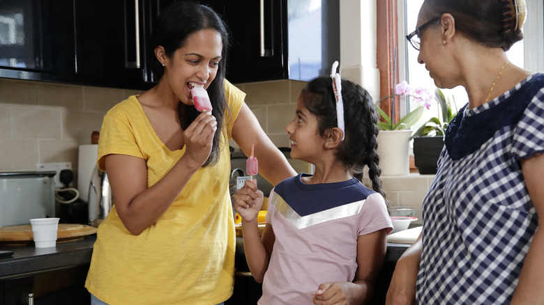 Family eating popsicles in kitchen