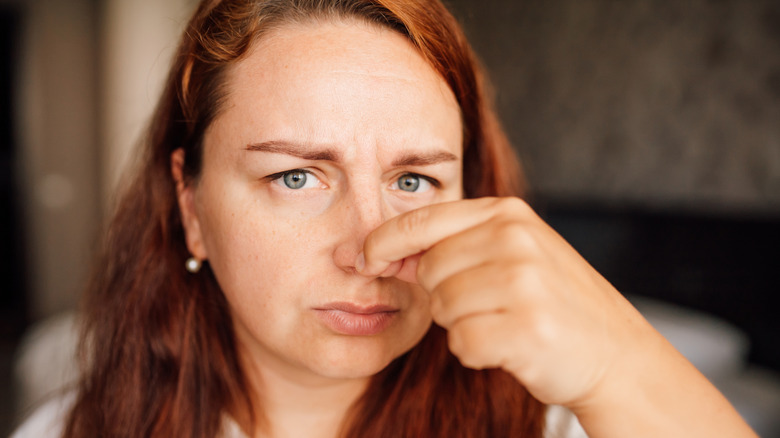 a woman holding her nose and cringing