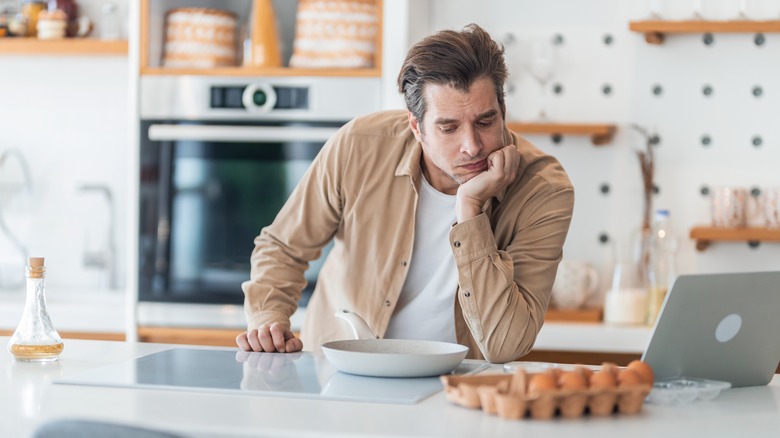 man considering how to make eggs in kitchen