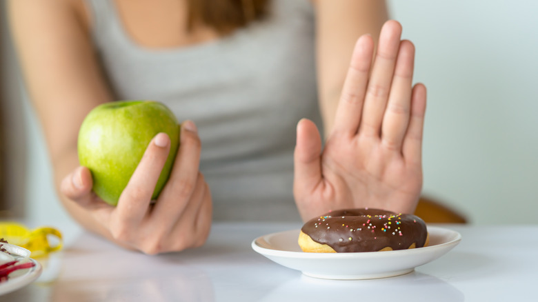 woman holding apple saying no to sweets