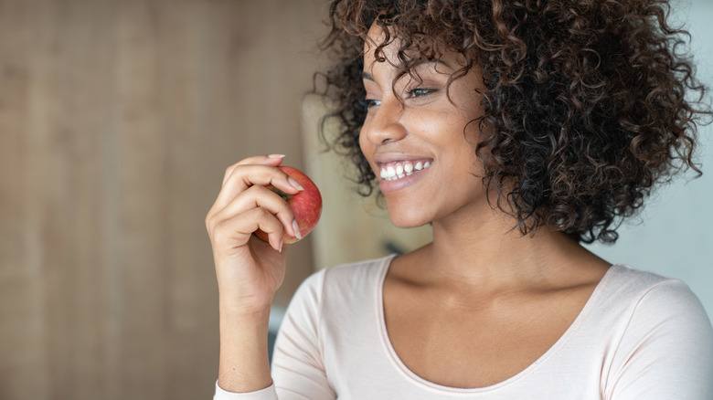 woman smiling holding red apple