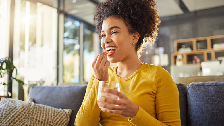 Happy woman taking medication with water