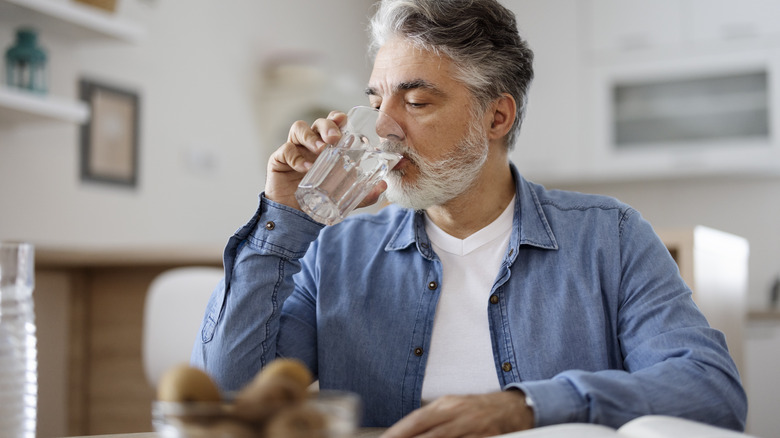Older man drinking water while sitting