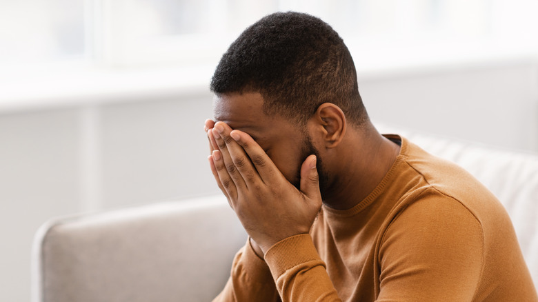 Man sitting holding his face in his hands