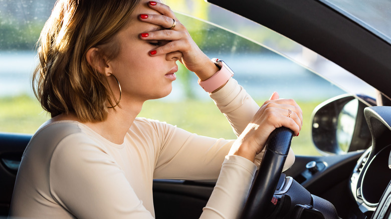 woman face-palming while driving