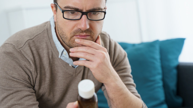 man looking at supplement bottle