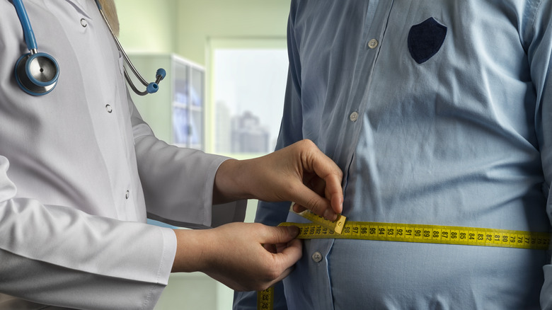 doctor measuring man's waist