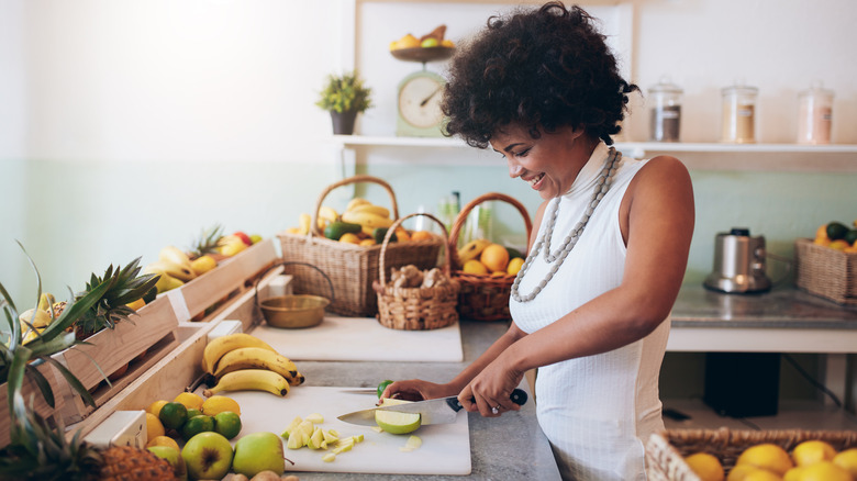 Smiling woman chopping fruit