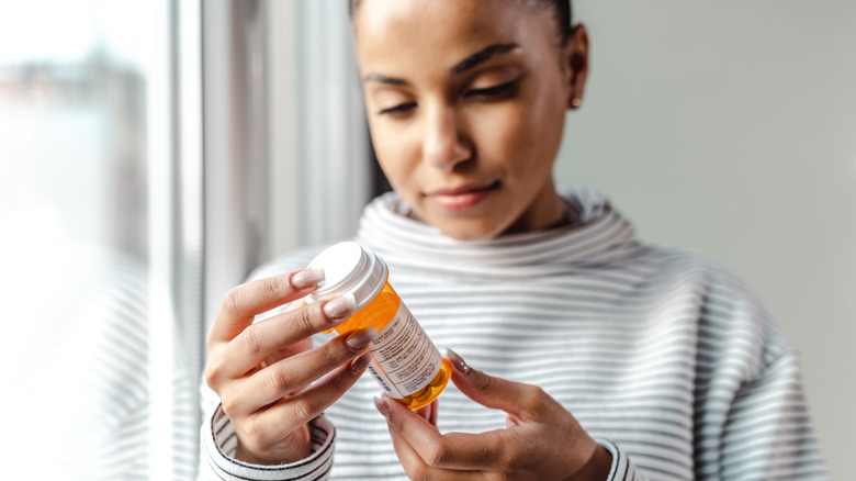 woman looking at her medication bottle