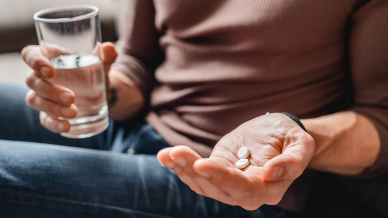 woman's hands holding medication and a glass of water