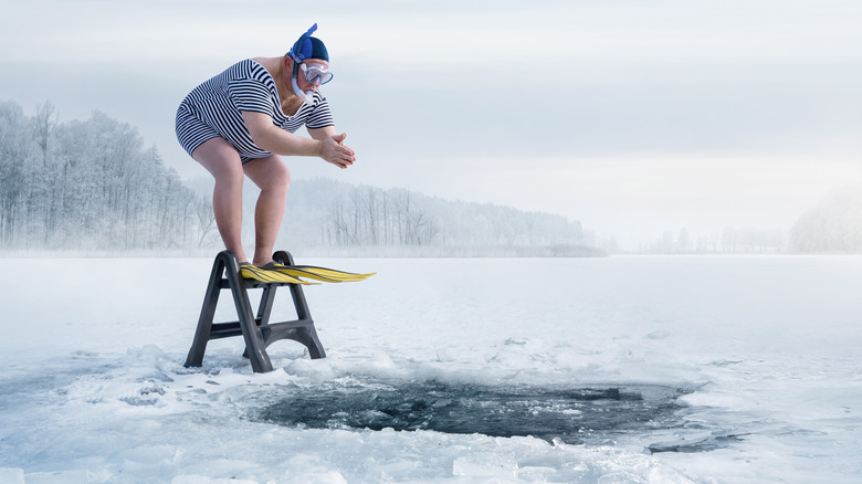 large man wearing goggles and a snorkel about to dive into an ice cold lake