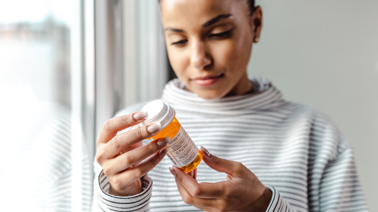 Woman looking at medicine bottle