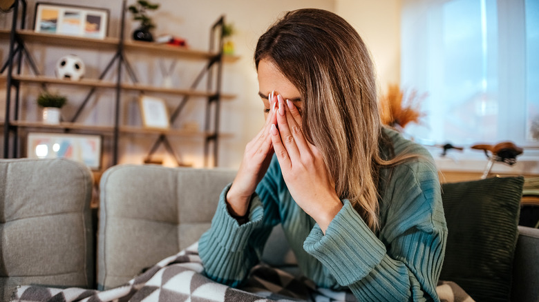 Woman with head in hands feeling nausea