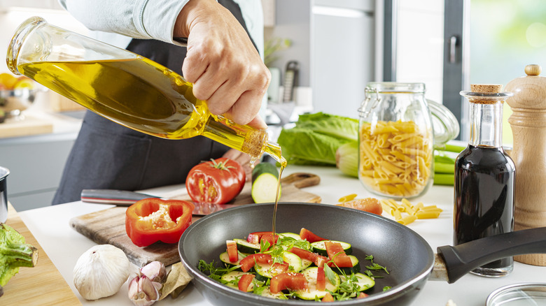 pouring olive oil over pan of vegetables