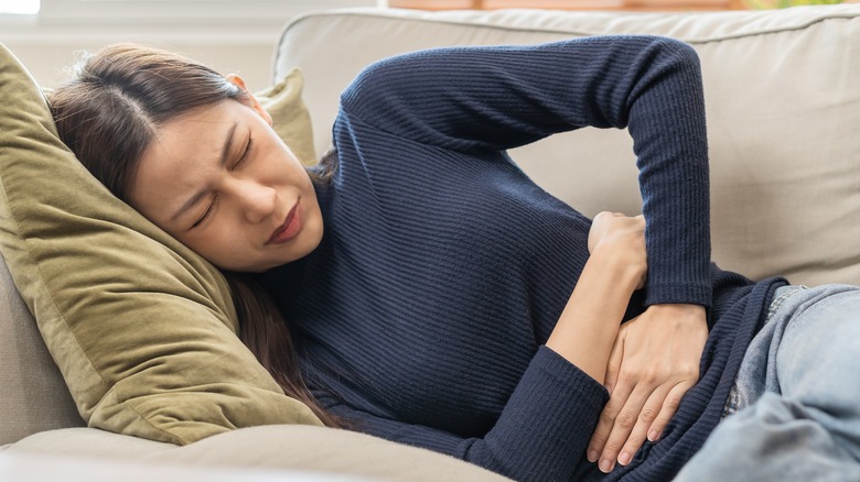 woman clutching her abdominal area with two hands