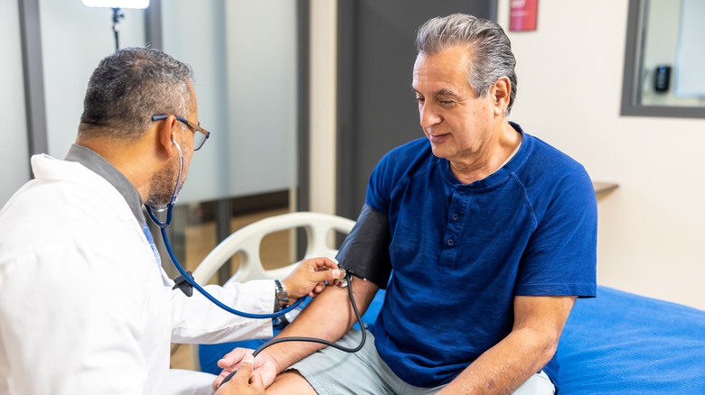 A doctor using a stethoscope to hear a man's pulse