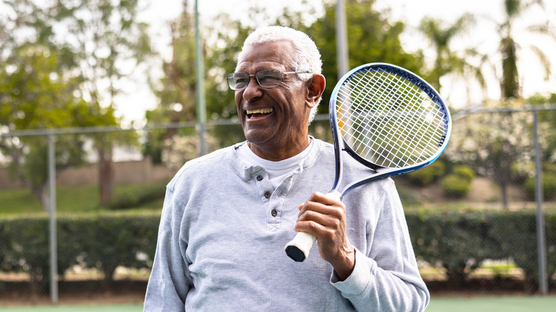 smiling older man holding a tennis racket
