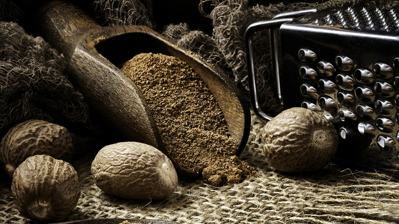 nutmeg seeds and powdered nutmeg on a rustic table