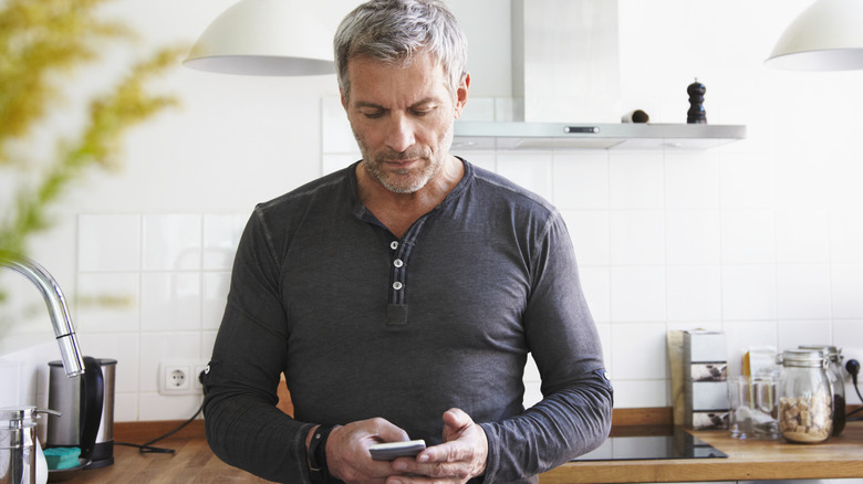 middle-aged male looking at his phone in the kitchen