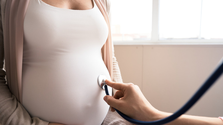 Stethoscope held to woman's pregnant belly