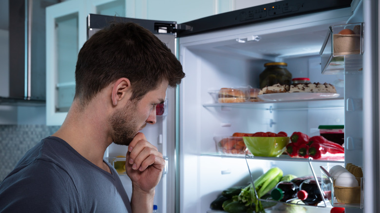 man checking fridge for snacks