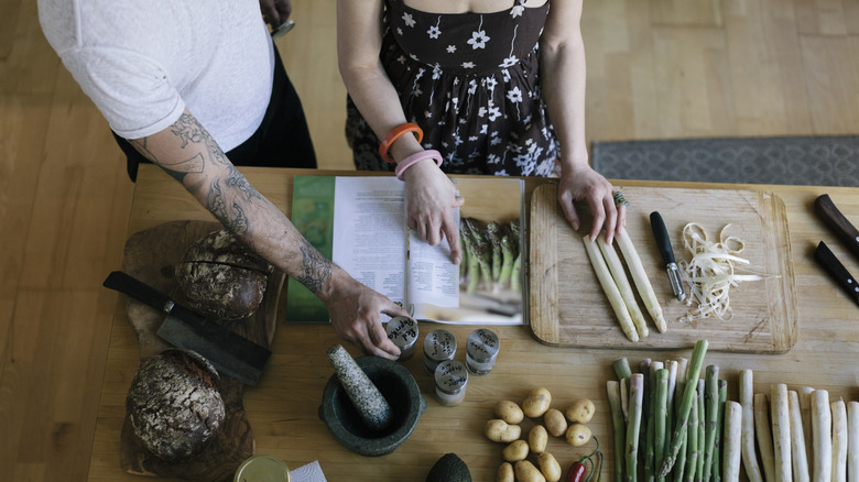 people reading a recipe book and preparing asparagus