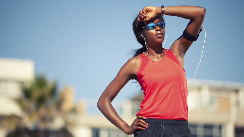 woman in running clothes looking into the sun during a summer run