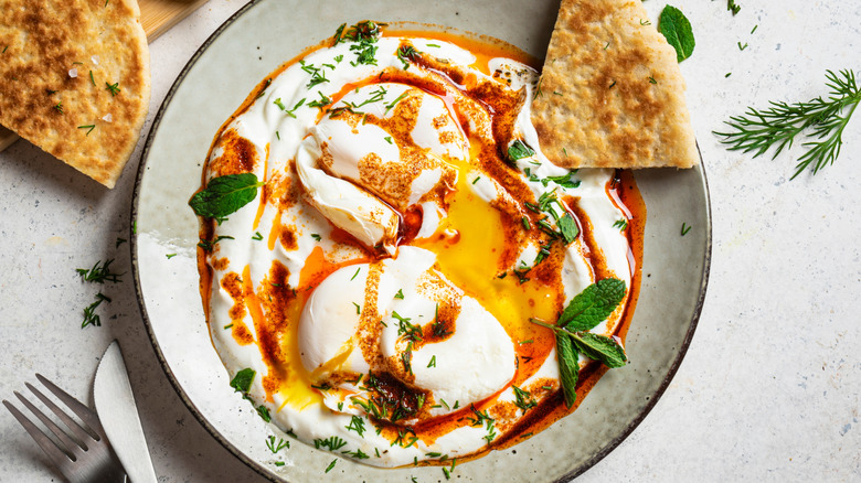 A plate of Turkish eggs with a slice of pita bread