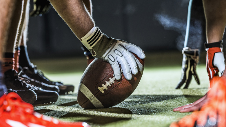 A football on the field held by a football player