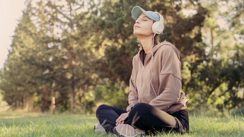 A woman with headphones sitting outdoors in peace