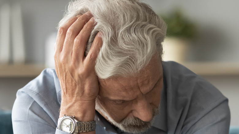 old man holding head in hands