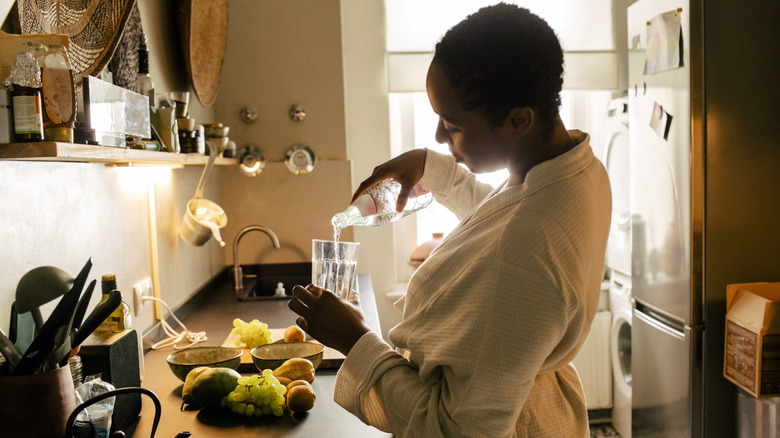 woman pouring water into a glass in a kitchen